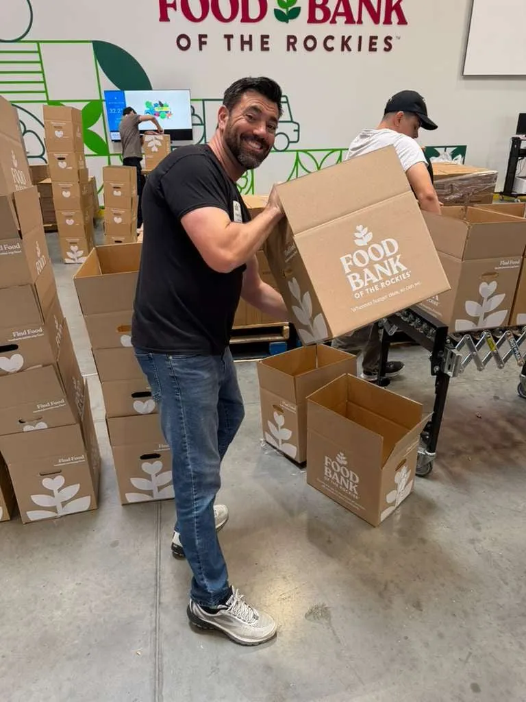 A volunteer packs a Food Bank of the Rockies box at a warehouse distribution shift